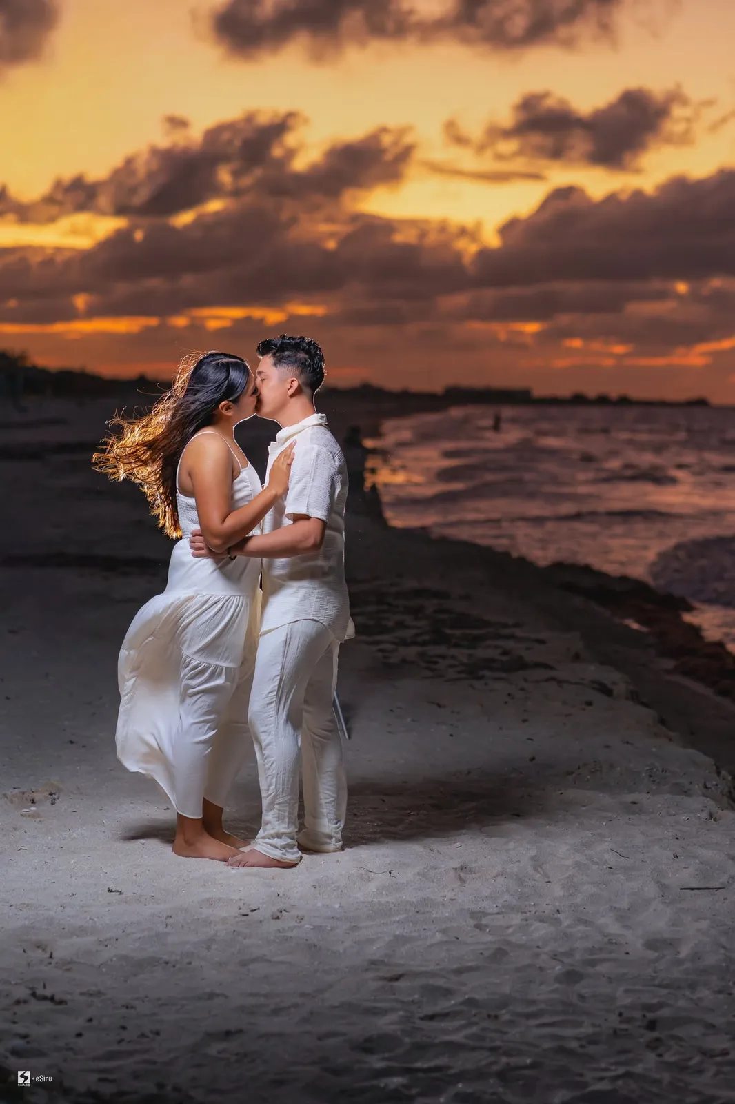 Novios besándose en la playa al atardecer